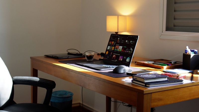 Escritório com notebook aberto sobre a mesa e luz da janela
