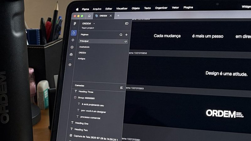 Garrafa preta da ORDEM ao lado do notebook aberto na mesa