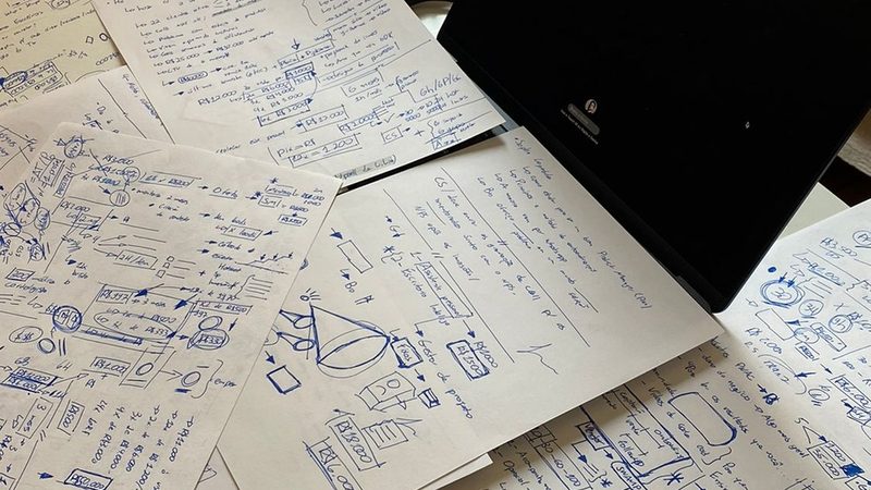 Folhas de anotações e esboços espalhadas sobre a mesa de trabalho