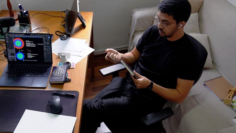 João Torres sentado no escritório, com um tablet na mão e o notebook aberto na mesa